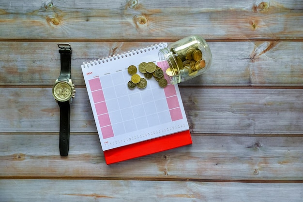A calendar with the months marked off, showing progress towards a 12-month goal. Money is placed on the calendar to symbolize savings milestones.