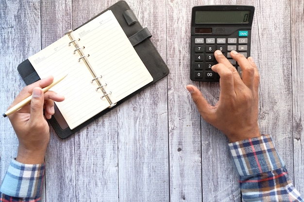 A person holding a credit card next to a calculator, with papers and charts showing interest rate calculations on a desk.