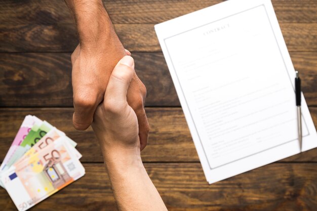 A close-up of hands exchanging stock certificates, symbolizing the transfer of company ownership and the benefits of employee stock options. Focus on trust and financial exchange.