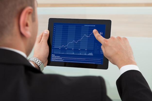 A close-up of a financial analyst reviewing a corporate earnings report on a tablet, with stock charts and data visualizations in the background.