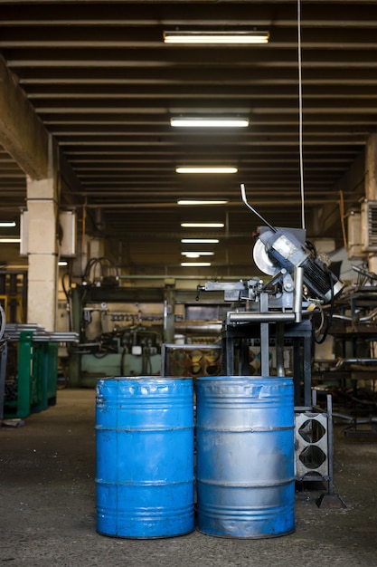 A factory assembly line with various products being manufactured, with oil barrels in the background signifying energy input in production processes and the potential impact on costs.