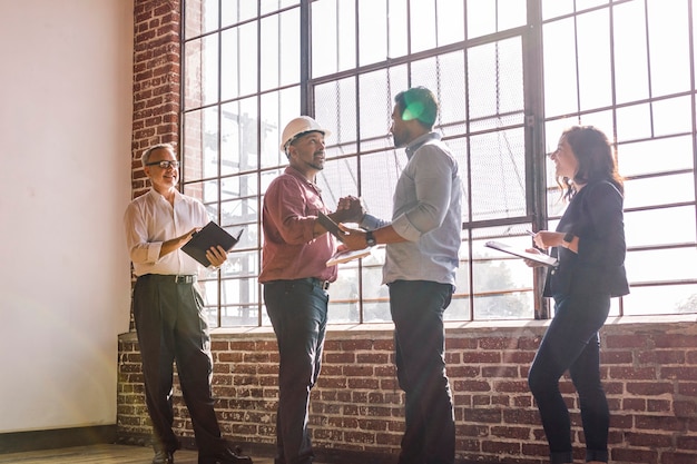A group of construction workers in hard hats inspecting blueprints at a construction site. The focus is on their collaboration and dedication to the project's success.