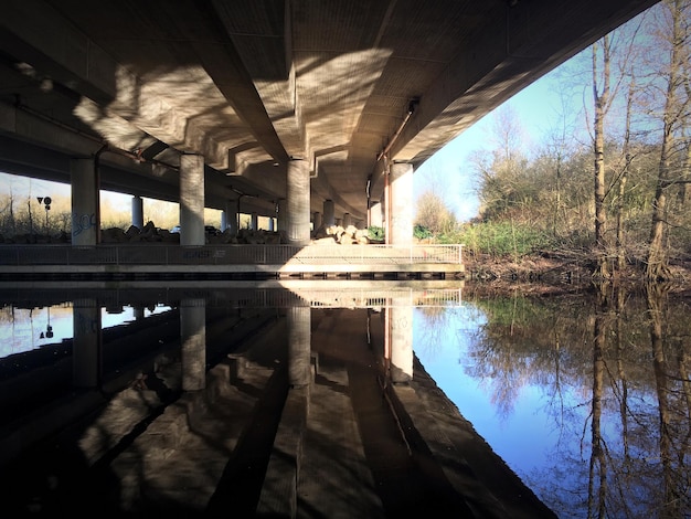 A modern concrete and steel bridge spanning a wide river, with cars and trucks traveling across it. The image represents the tangible results of infrastructure development and improved transportation.