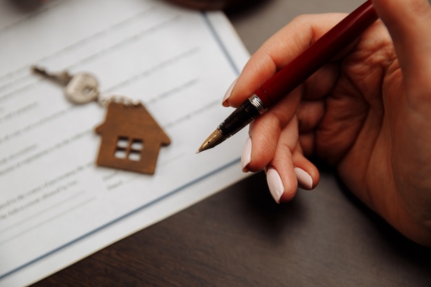 A close-up shot of a hand signing a mortgage document with a pen. The focus is on the signature, symbolizing a commitment to new financial terms.