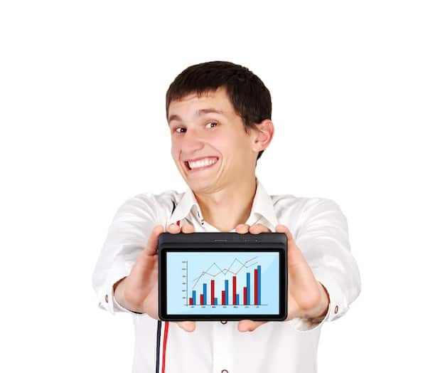 A person smiling while looking at a tablet showing graphs with upward trends, representing the tax-free growth of an HSA investment.