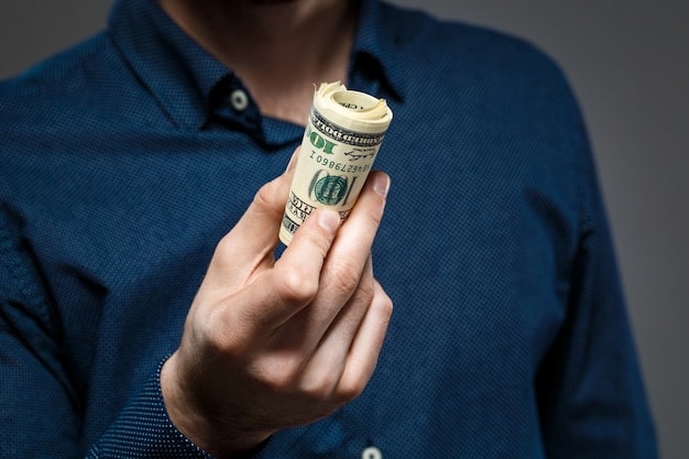 A close-up shot of a hand holding US currency, symbolizing the financial impact of the COLA increase on Social Security recipients.
